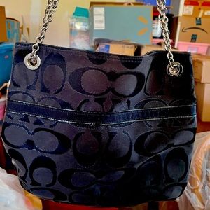 Black coach handbag with metal straps.